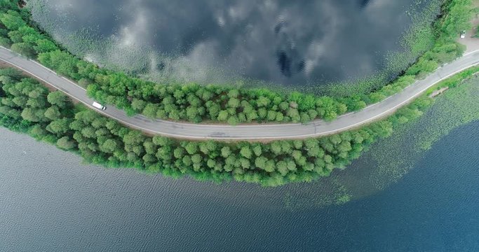 Punkaharju Finland, cars drive past on a very narrow road surrounded by water