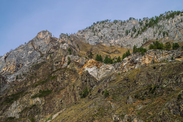 Beautiful rocky green mountain with greenery. Natural textured background with rock and sky.