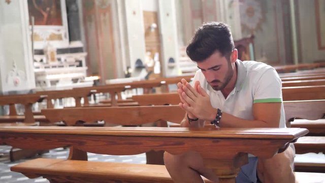 Young man sitting and kneeling in church praying