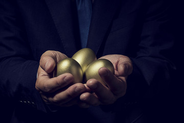 金の卵を手に持ったビジネスマン