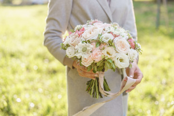 Young girl holding a beautiful spring bouquet. flower arrangement with garden roses. Color light pink. Bright dawn or sunset sun