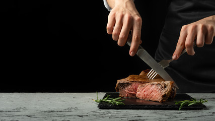Chef, cut with a meat steak on a black background with an open space for text or restaurant menus. Horizontal photo Black text area. - 220461709