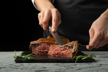 Chef, sliced with meat steak on a black background, Recipe concept for homemade food. A larger plan