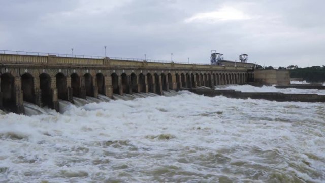 A view of a big reservoir with its flood gates open and massive quantity of water flowing through it.