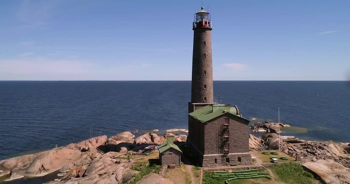 C4K aerial drone view away from a tall lighthouse on a rocky island bengtskar, on a sunny summer day, in saaristomeri national park, Varsinais-suomi, Finland