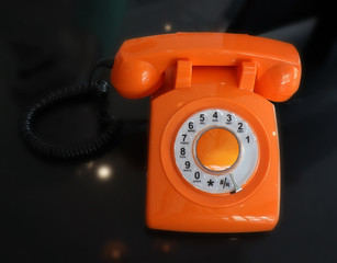 Old Fashioned Orange Vintage Rotary Dial Telephone. Black background.