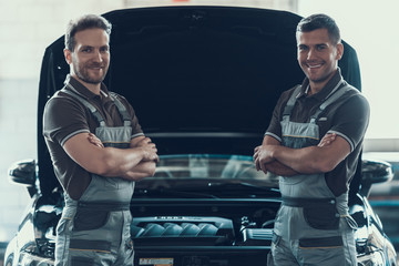 Two Mechanics Standing Near Car with Crossed Arms