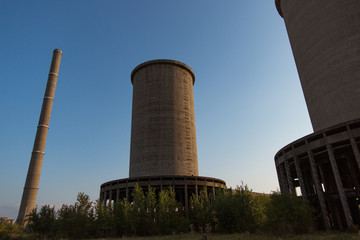 A deserted industrial plant site with big towers on a beautiful sunset.