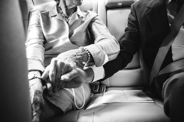Elderly Couple Holds Hands in Car 