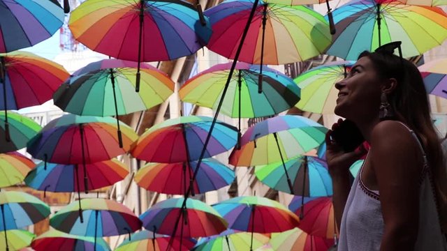 Girl Talking On The Phone Looking At Colored Umbrellas In Awe Slow Motion