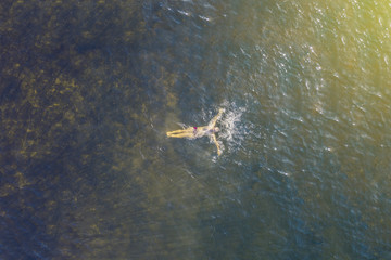 top high aerial view of lonely person swim in the sea in a summer heaven lagoon beach
