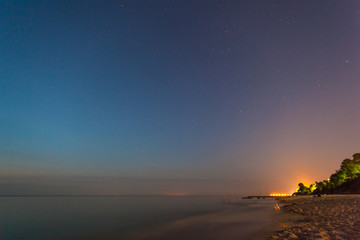 smooth sea surface and coast at twilight under the stars for long exposure