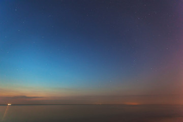 Fototapeta premium smooth sea surface at twilight under the stars for long exposure, toned
