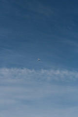 A model airplane does acrobatics in a blue sky with light clouds