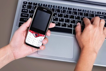 Male hands with phone on laptop  on office table