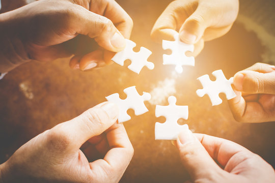 Hand Of Diverse People Connecting Jigsaw Puzzle. Concept Of Partnership And Teamwork In Business