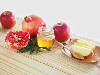 Apples, pomegranates and honey on the wooden board have space for text or symbol with the concept food selected at the Jewish holiday rosh hashanah.