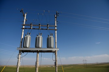 Electrical grid infrastructure and rural farming in Wyoming. Green fields and a clear blue sky with Copy Space.