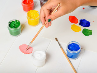 The girl picks up the pink color in the palette on a table.