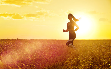 Sporty woman at sunset in wheat field