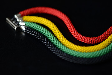 Bead crochet bracelet in Jamaican style on a dark background close up
