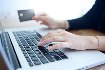 female hands holding credit card and using laptop for online shopping