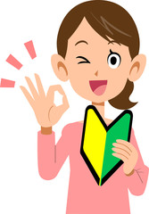 初心者マークを左手に持ち、右手でOKのサインを示す女性
