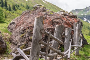 Riesiger Stein Findling auf einer Weide und zerstörtem Holzzaun, Österreich