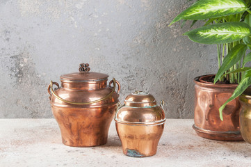 Two vintage copper jars with lids on a concrete background.