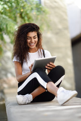 Obraz premium Young black woman in sportswear using digital tablet outdoors