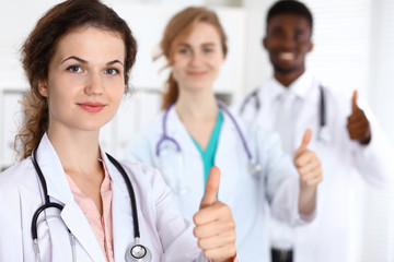 Fototapeta premium Medical team of confident doctors showing Ok sign with thumbs up. Medicine and health care, insurance concept