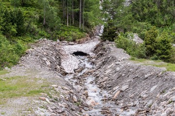 Reste der Eisdecke und Schneedecke über einen Gebirgsbach im Sommer, Österreich