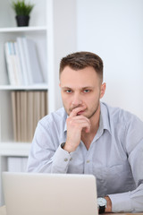 Portrait of businessman sitting at the desk in office workplace