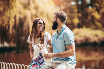 Young couple in park eating popcorn on beautiful sunny day
