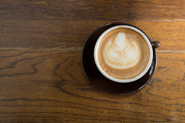 Closeup latte art of coffee brown cup on wooden table surface