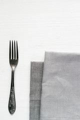 Steel fork and gray cloth napkins on a white wooden table