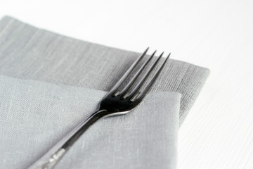 Steel fork and gray cloth napkins on a white wooden table