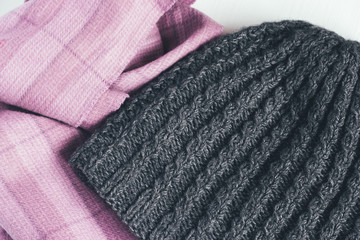 Gray woolen knitted hat and pink scarf on a white background