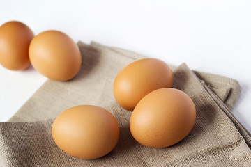 Brown chicken eggs on burlap on a white background