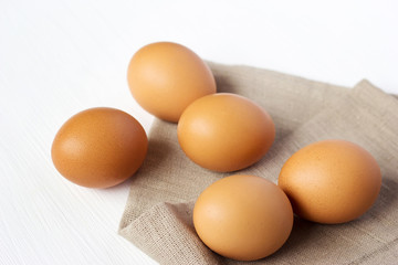 Brown chicken eggs on burlap on a white background