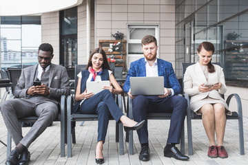 Group of happy diverse male and female business people team in formal gathered around laptop computer in bright office against the background of a glass building