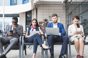 Group of happy diverse male and female business people team in formal gathered around laptop computer in bright office against the background of a glass building