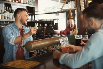 Bartender working at beer tap in pub