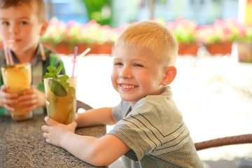 Fototapeta premium Cute children with natural lemonade at table in cafe