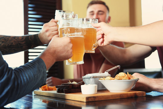 Friends clinking glasses with beer in pub