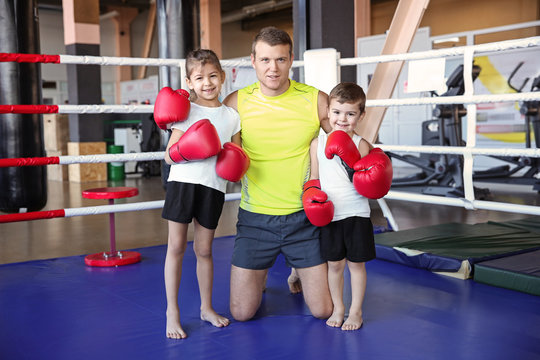 Little children with trainer in boxing ring