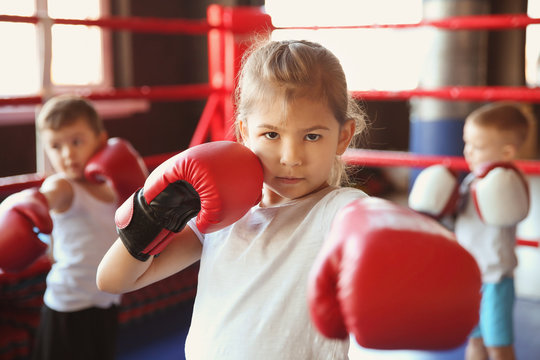 Little girl in boxing gloves on ring