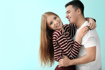 Cute young couple hugging against color background