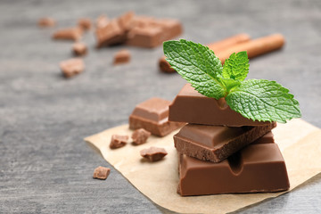 Pieces of milk chocolate with mint on gray table