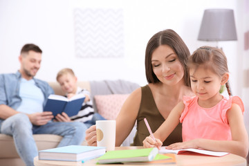 Cute little girl doing homework with mother